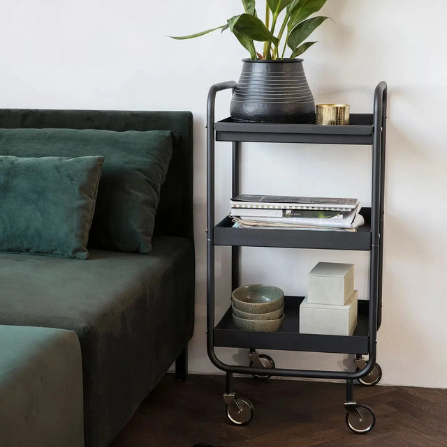 House Doctor Servierwagen Roll in Schwarz mit drei Ebenen neben einem Sofa