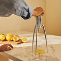 Alessi Zitruspresse Juicy Salif in Anwendung – frisch gepresster Zitronensaft läuft ins Glas