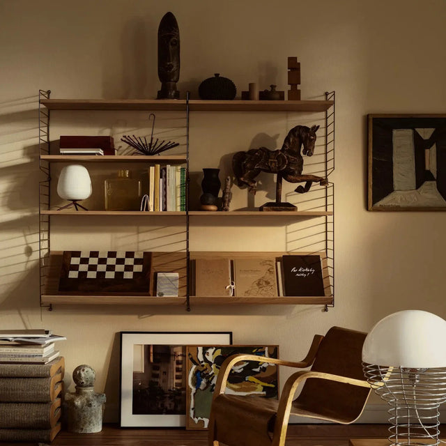 String Wandregal Vorteilsset mit Eichenböden, dekoriert mit Büchern, Lampe und Skulpturen neben einem Sessel